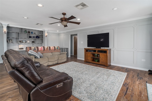 living room with visible vents, crown molding, a decorative wall, and dark wood-type flooring