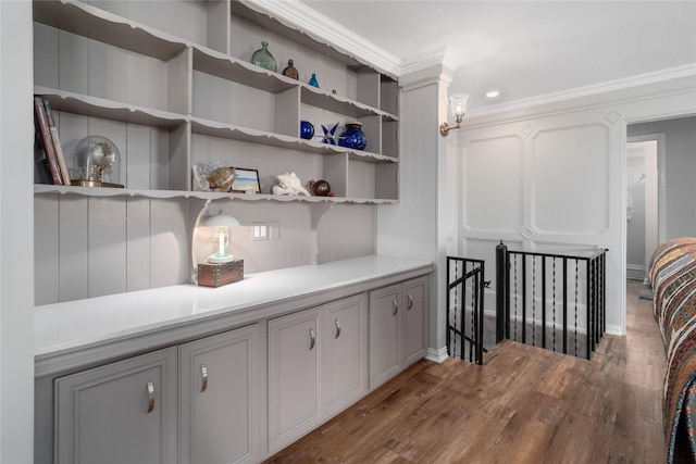 interior space featuring light countertops, wood finished floors, ornamental molding, and a decorative wall