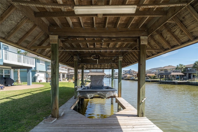 dock area featuring boat lift, a yard, and a water view