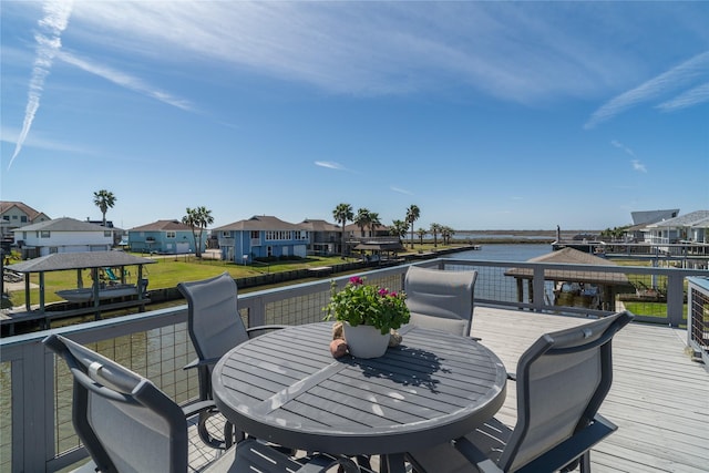 deck with a residential view, outdoor dining area, and a water view