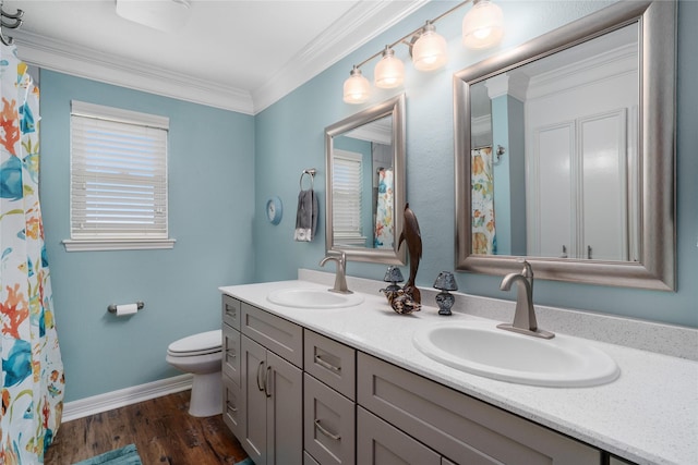 bathroom with toilet, wood finished floors, crown molding, and a sink