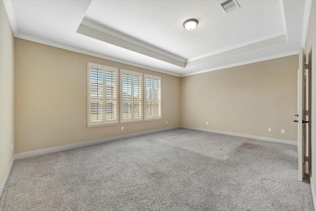 carpeted spare room with visible vents, a raised ceiling, baseboards, and crown molding