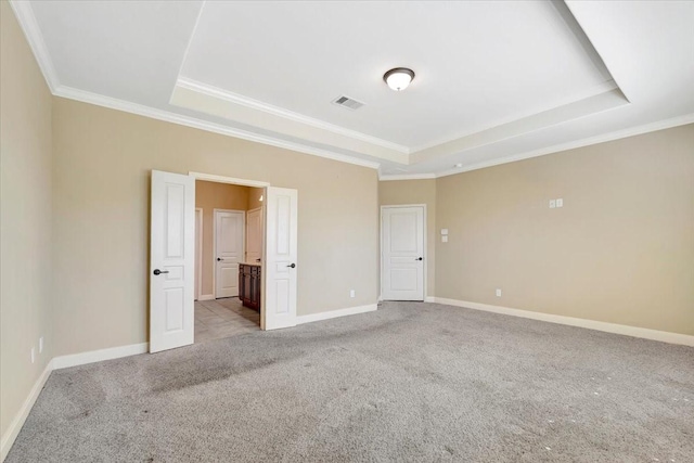 empty room with a raised ceiling, baseboards, visible vents, and carpet floors