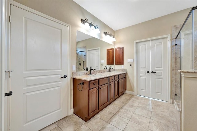 bathroom featuring a sink, tile patterned flooring, double vanity, and a tile shower