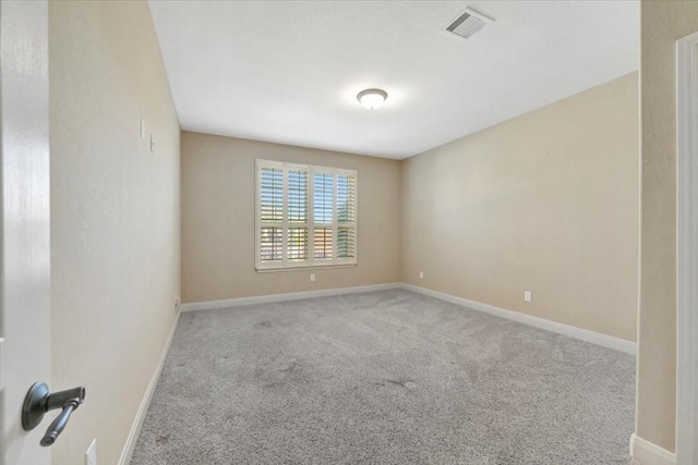 carpeted spare room featuring baseboards and visible vents