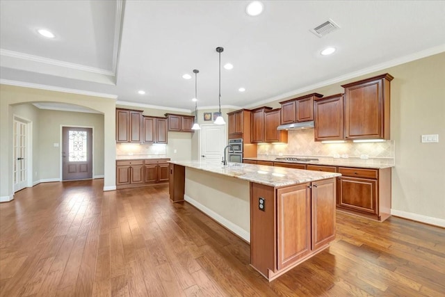 kitchen featuring visible vents, arched walkways, stainless steel gas stovetop, and wood-type flooring