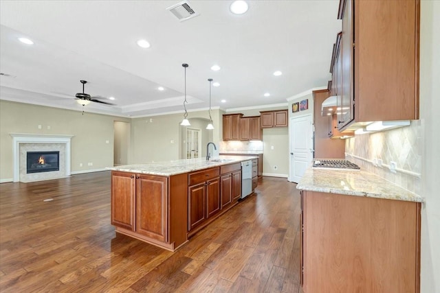 kitchen with visible vents, a sink, range hood, open floor plan, and brown cabinetry