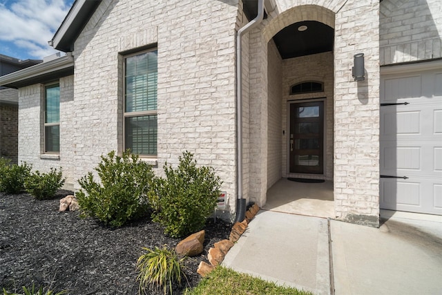 entrance to property with brick siding and an attached garage