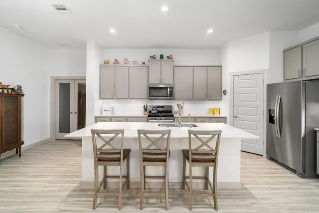 kitchen with visible vents, gray cabinets, a sink, stainless steel appliances, and light countertops