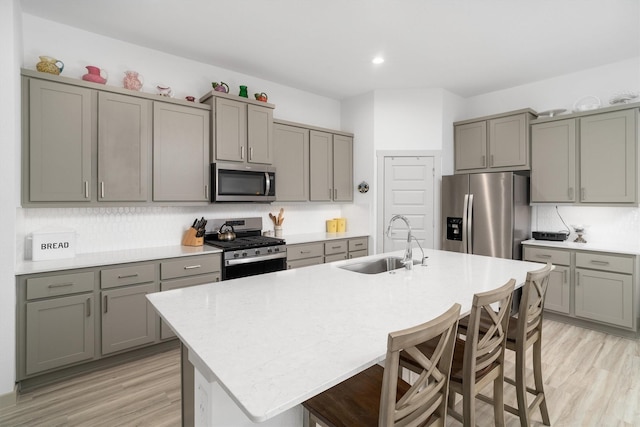 kitchen featuring a sink, gray cabinetry, light wood finished floors, and stainless steel appliances