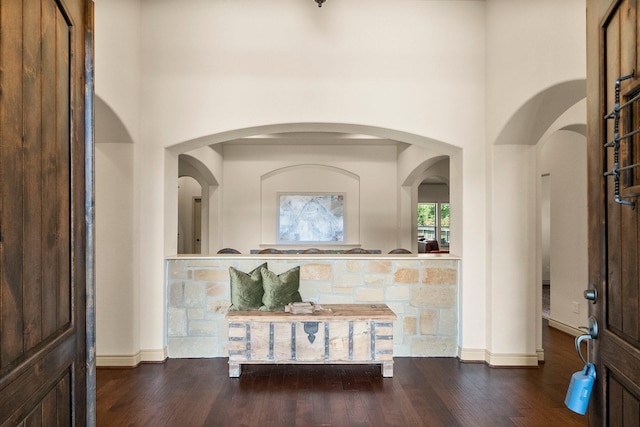 interior space with baseboards, a high ceiling, and wood finished floors