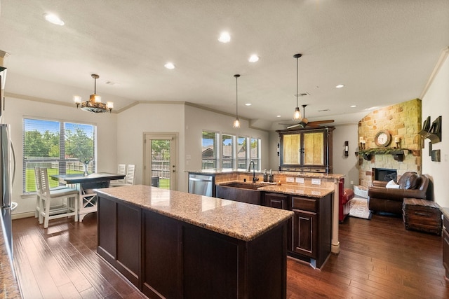 kitchen featuring a center island with sink, a sink, open floor plan, dark wood-style floors, and stainless steel appliances