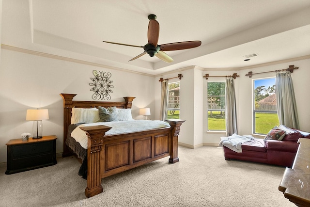 bedroom with visible vents, crown molding, light colored carpet, a raised ceiling, and a ceiling fan