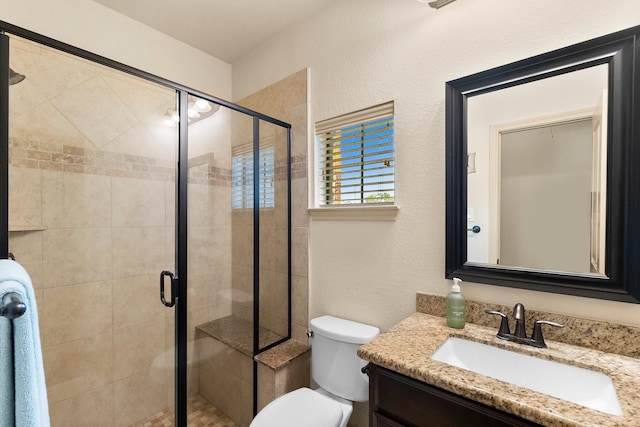 full bath featuring a shower stall, vanity, toilet, and a textured wall