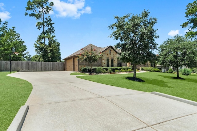 view of front of home with a front yard, fence, an attached garage, concrete driveway, and stone siding