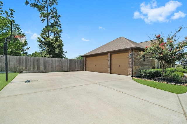 view of home's exterior featuring brick siding, a shingled roof, an attached garage, and fence