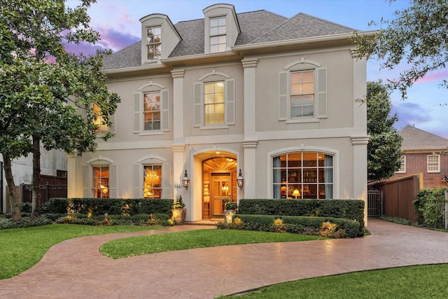 view of front of house with a shingled roof, fence, and stucco siding