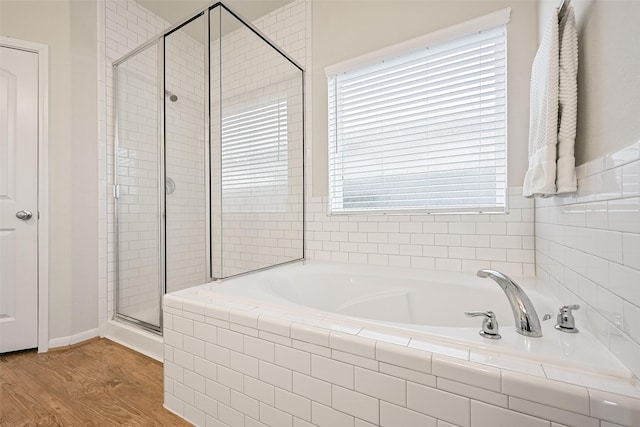 full bathroom with a shower stall, a garden tub, and wood finished floors