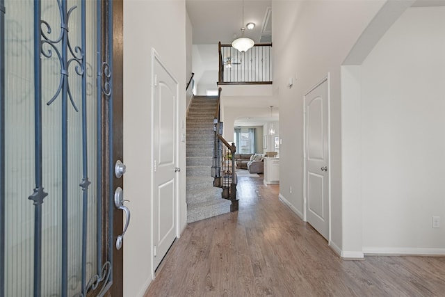 entrance foyer featuring arched walkways, stairway, and wood finished floors