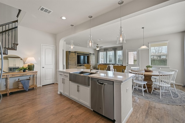 kitchen with visible vents, light wood-style flooring, arched walkways, a sink, and dishwasher