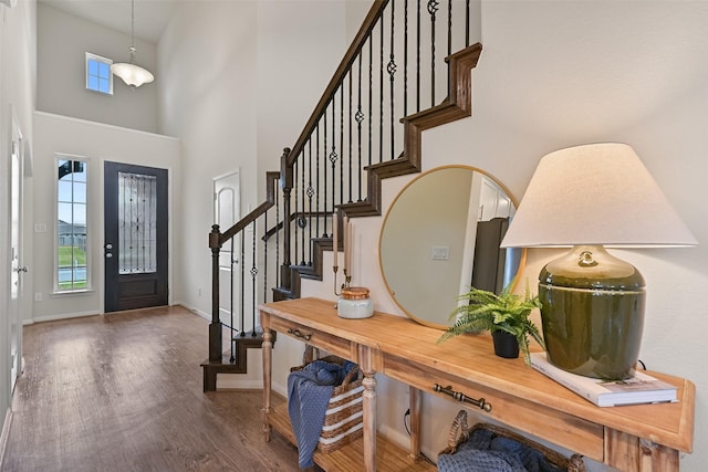 entrance foyer with stairs, baseboards, a high ceiling, and dark wood-style flooring