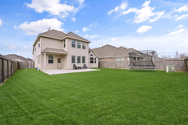 rear view of property with a patio area, a fenced backyard, a lawn, and a trampoline