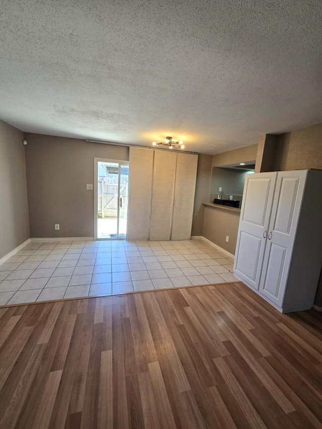 interior space with light wood-style flooring, baseboards, and a textured ceiling