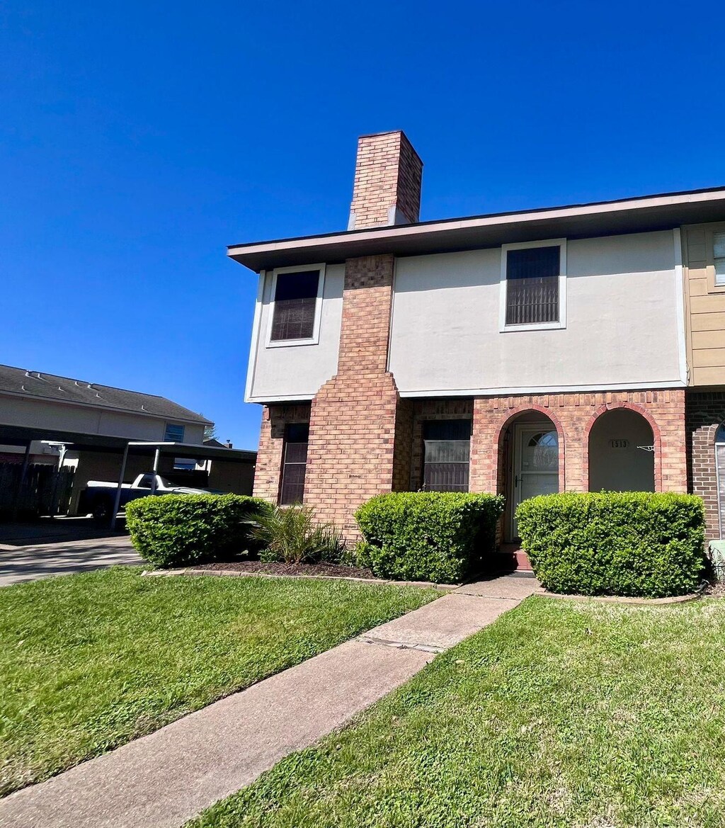 1513 Bonanza Rd Unit 513, Houston, TX 77062 - view of front facade featuring a chimney, brick siding, and a front lawn