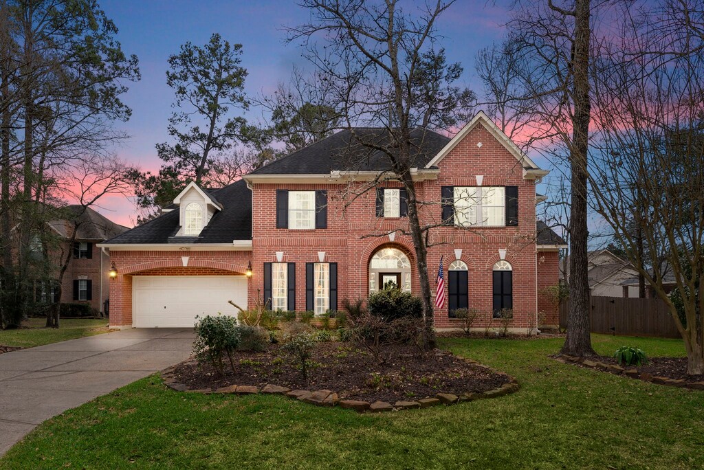 10 Millwright Pl, The Woodlands, TX 77382 - view of front of house with a lawn, driveway, fence, a garage, and brick siding