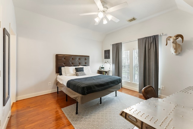 bedroom featuring light wood-type flooring, visible vents, baseboards, ceiling fan, and vaulted ceiling