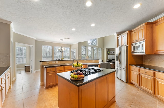 kitchen with dark countertops, a center island with sink, and stainless steel appliances