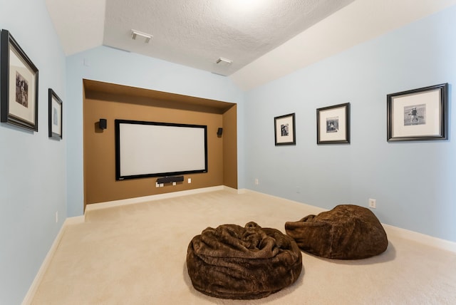 home theater room with vaulted ceiling, carpet, visible vents, and a textured ceiling