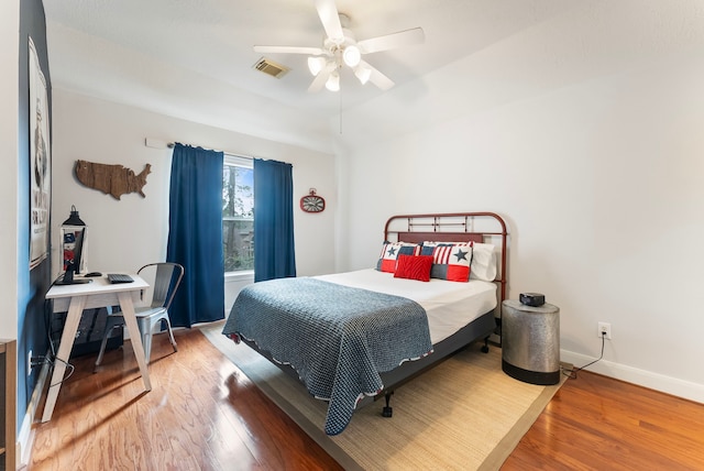 bedroom featuring ceiling fan, wood finished floors, visible vents, and baseboards