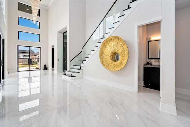 entrance foyer with stairway, baseboards, ornamental molding, a towering ceiling, and marble finish floor