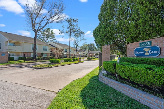 community / neighborhood sign with concrete driveway, fence, and a residential view