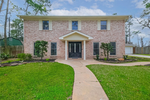 colonial house with a front yard, fence, and brick siding