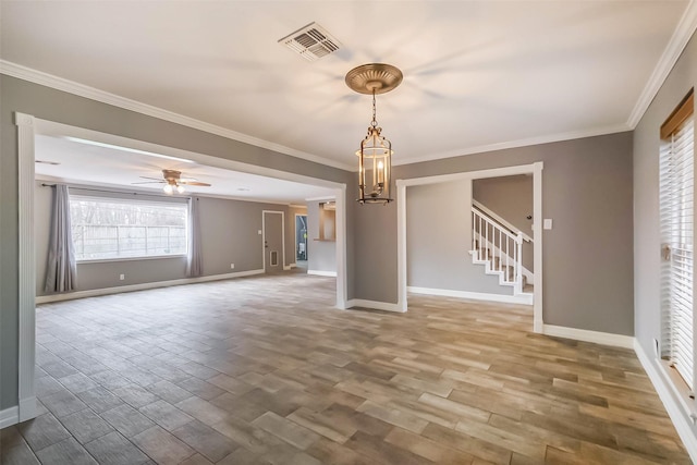 spare room featuring crown molding, stairway, wood finished floors, and visible vents