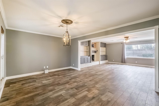 unfurnished living room with visible vents, a brick fireplace, baseboards, ornamental molding, and dark wood-style flooring