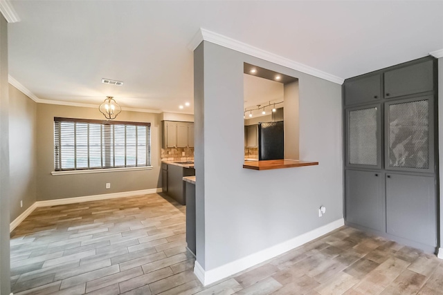 kitchen featuring decorative backsplash, crown molding, visible vents, and freestanding refrigerator