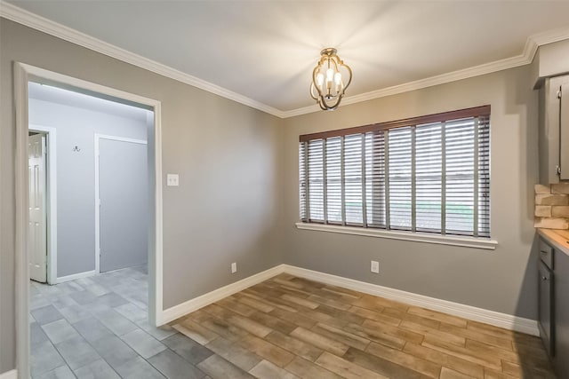 unfurnished dining area with crown molding, a notable chandelier, wood finished floors, and baseboards