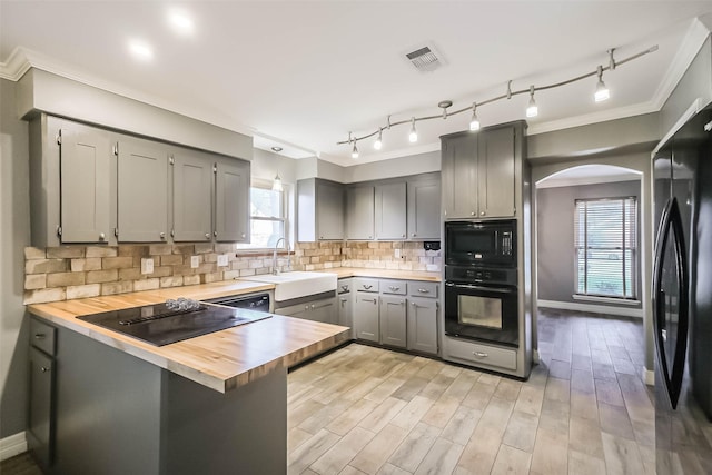 kitchen featuring visible vents, black appliances, gray cabinets, a sink, and backsplash