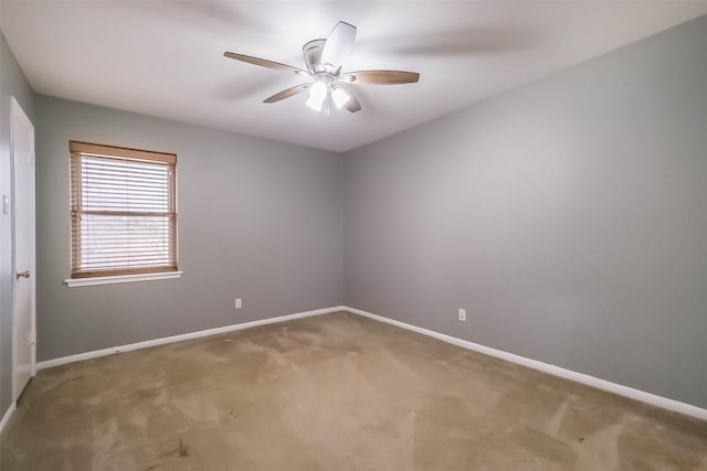 carpeted empty room with a ceiling fan and baseboards