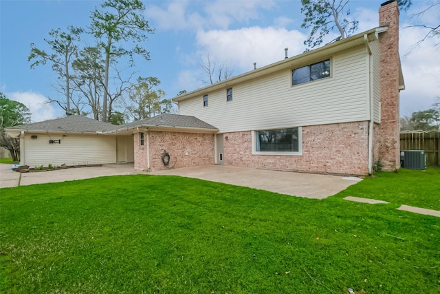 rear view of property with central AC, a chimney, concrete driveway, a patio area, and a lawn