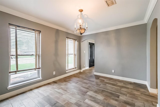 spare room featuring visible vents, arched walkways, plenty of natural light, and an inviting chandelier