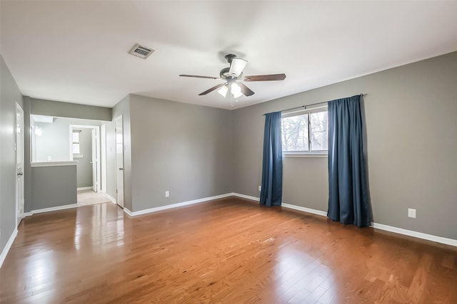 unfurnished room featuring visible vents, baseboards, wood finished floors, and a ceiling fan