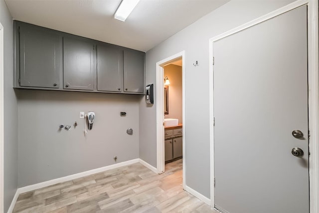 washroom featuring cabinet space, baseboards, light wood-style floors, and hookup for a gas dryer