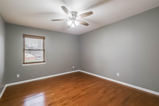 unfurnished room with baseboards, wood finished floors, and a ceiling fan