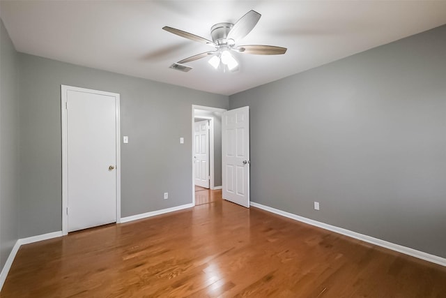 unfurnished bedroom with ceiling fan, visible vents, baseboards, and wood finished floors