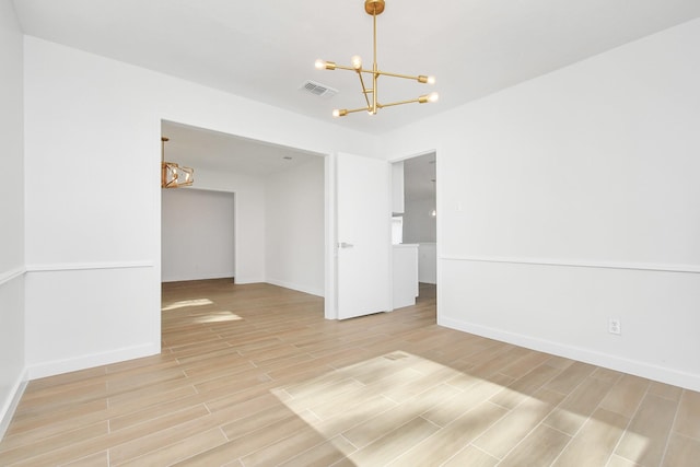 empty room with light wood-style floors, visible vents, baseboards, and a notable chandelier