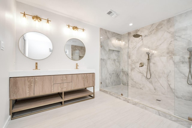 bathroom with visible vents, a sink, a marble finish shower, double vanity, and baseboards